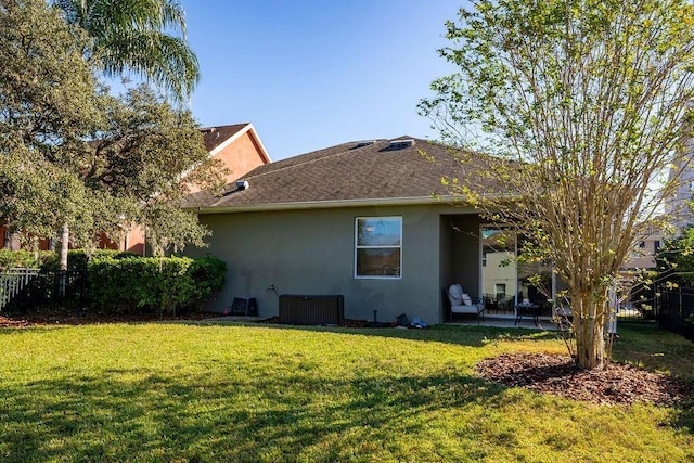 rear view of property with a lawn and central air condition unit