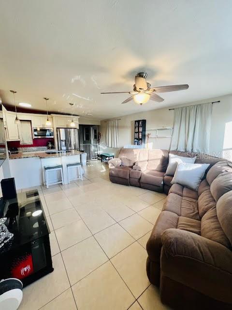 living room featuring ceiling fan and light tile patterned floors