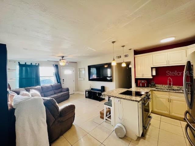 kitchen with range with gas stovetop, sink, light tile patterned flooring, and pendant lighting