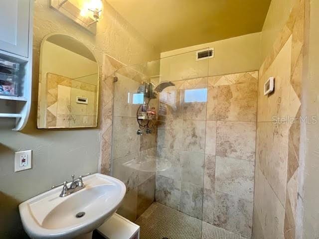 bathroom featuring a tile shower and sink