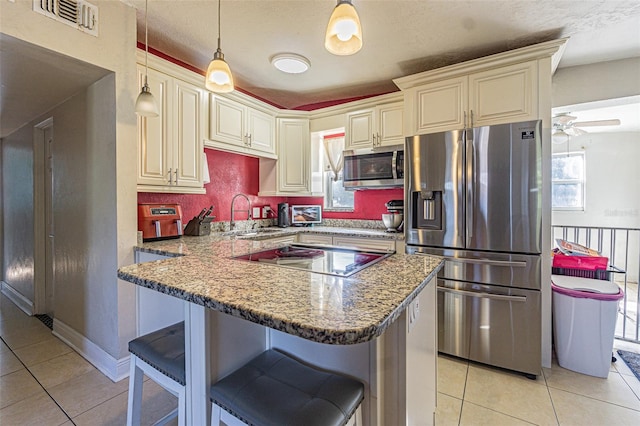 9696 Groveland St, Seminole, FL 33772 - kitchen with sink, a breakfast bar area, hanging light fixtures, stainless steel appliances, and cream cabinetry