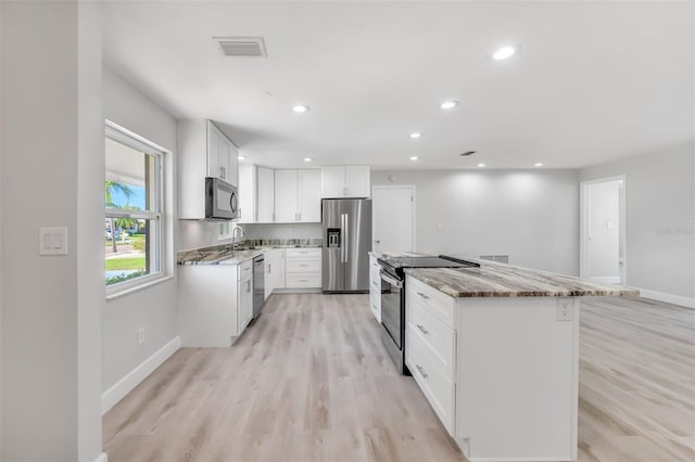 kitchen with white cabinetry, light hardwood / wood-style flooring, a kitchen island, and stainless steel appliances