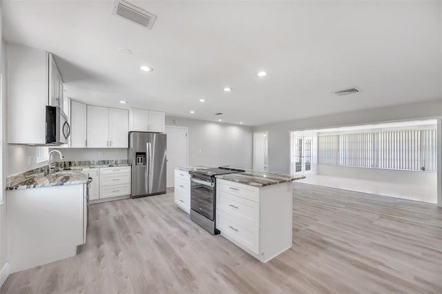 kitchen featuring a center island, white cabinets, appliances with stainless steel finishes, stone countertops, and light hardwood / wood-style floors