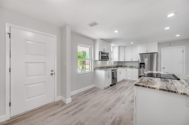 kitchen featuring white cabinets, sink, light hardwood / wood-style flooring, appliances with stainless steel finishes, and light stone counters