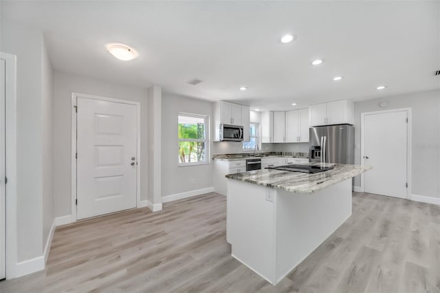 kitchen featuring light stone countertops, white cabinetry, light wood-type flooring, and appliances with stainless steel finishes