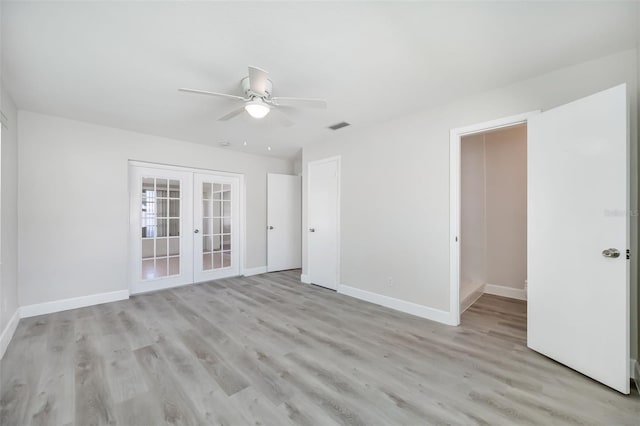 empty room with ceiling fan, light wood-type flooring, and french doors