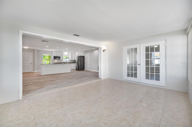 unfurnished living room with light wood-type flooring and french doors