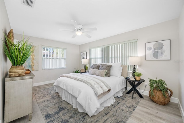 bedroom with light wood-style floors, baseboards, visible vents, and ceiling fan