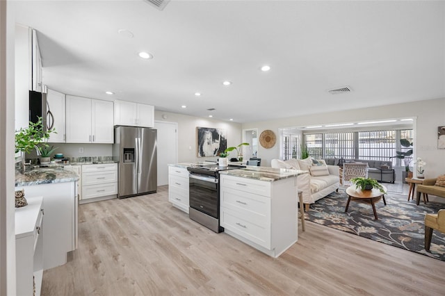 kitchen featuring recessed lighting, light wood-style flooring, appliances with stainless steel finishes, open floor plan, and a kitchen island
