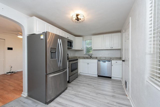 kitchen with backsplash, white cabinetry, stainless steel appliances, and light hardwood / wood-style floors