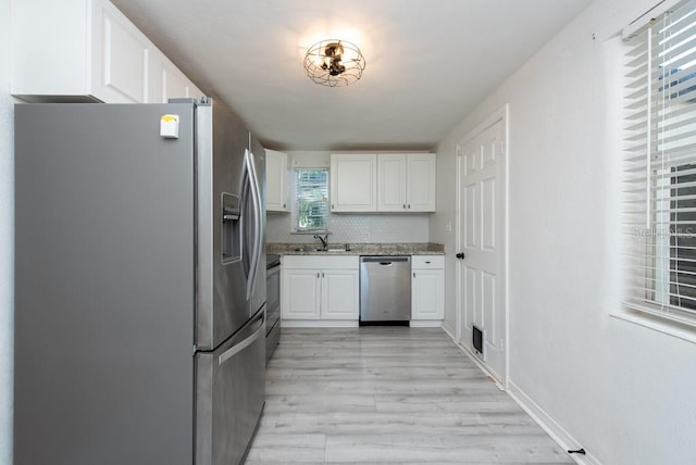 kitchen featuring white cabinets, light wood-type flooring, stainless steel appliances, and sink