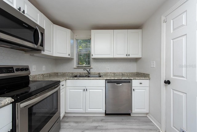 kitchen with appliances with stainless steel finishes, light hardwood / wood-style flooring, white cabinetry, and sink