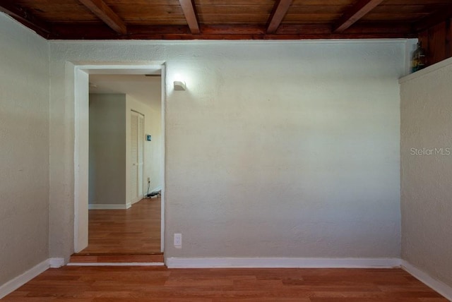 empty room with beam ceiling, wood ceiling, and hardwood / wood-style flooring