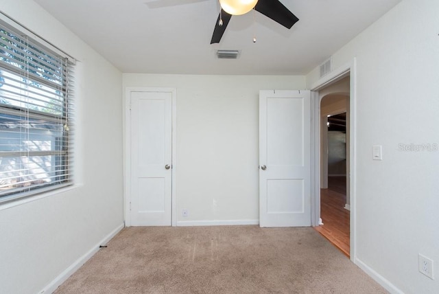 unfurnished bedroom featuring ceiling fan, a closet, and light carpet