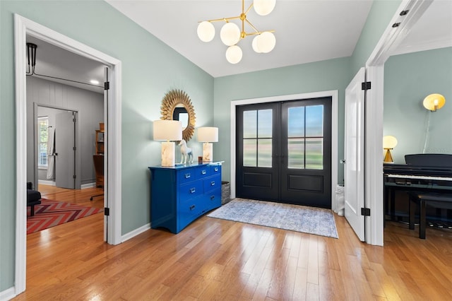 foyer with a notable chandelier, light hardwood / wood-style floors, and french doors