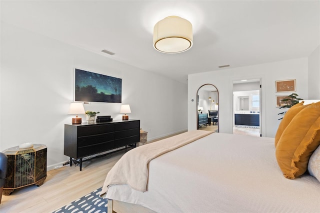 bedroom with light wood-type flooring and ensuite bath