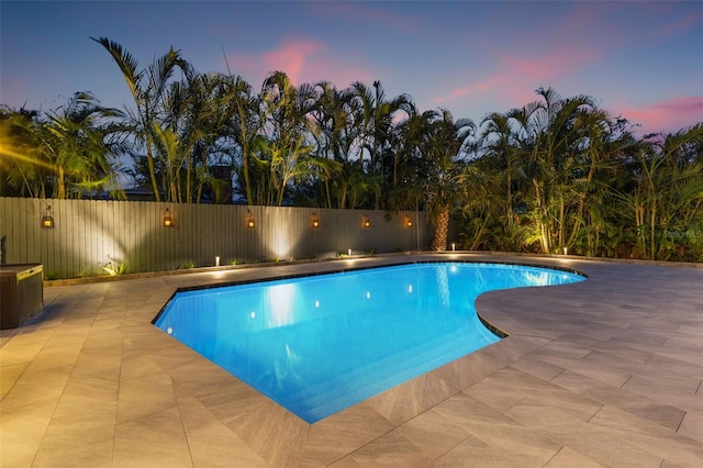 pool at dusk with a patio area