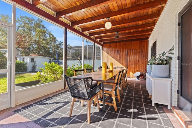 sunroom featuring beam ceiling, plenty of natural light, and wooden ceiling