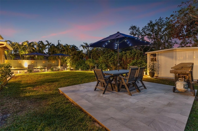 patio terrace at dusk featuring a storage shed and a yard