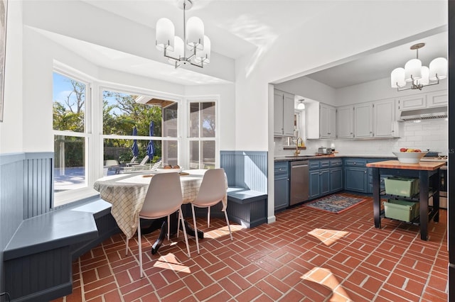 kitchen featuring dishwasher, an inviting chandelier, tasteful backsplash, blue cabinets, and decorative light fixtures