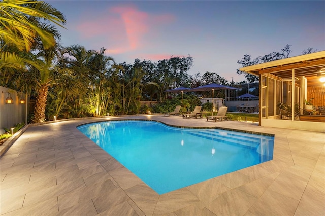 pool at dusk with a patio area