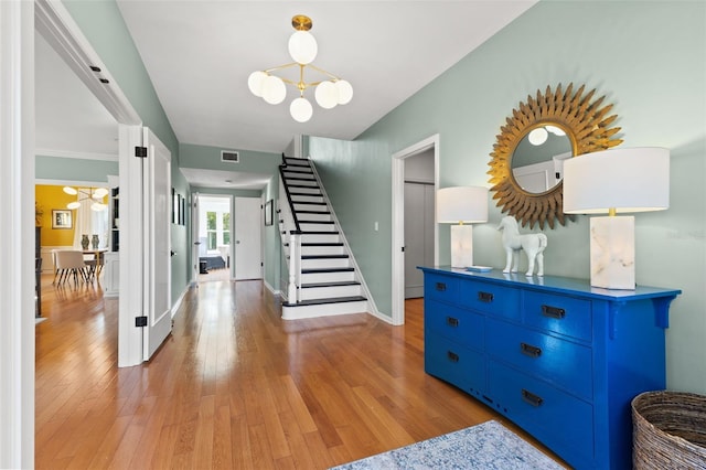 foyer featuring light hardwood / wood-style floors, an inviting chandelier, and ornamental molding