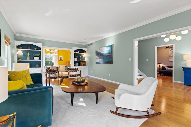 living room with built in shelves, wood-type flooring, and ornamental molding