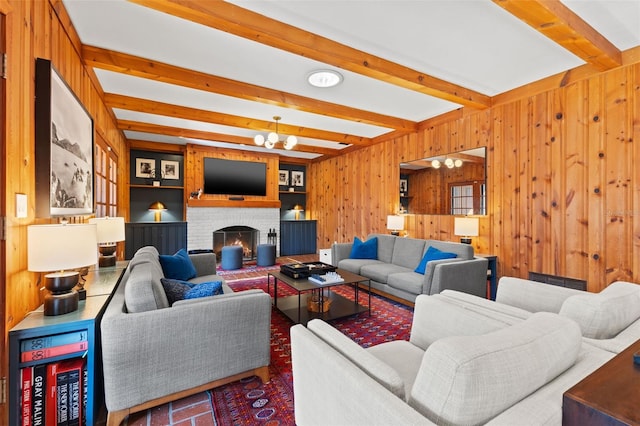 living room featuring beam ceiling, wood walls, a fireplace, and a chandelier