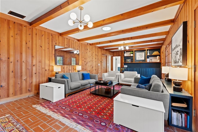 living room featuring wood walls, beam ceiling, and an inviting chandelier