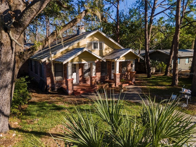 craftsman-style house with brick siding, a chimney, and stucco siding