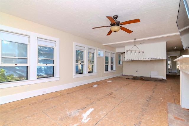 unfurnished living room with ceiling fan, a textured ceiling, and a wealth of natural light