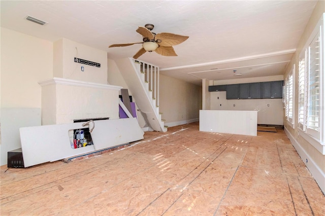 unfurnished living room featuring stairway, visible vents, and a ceiling fan