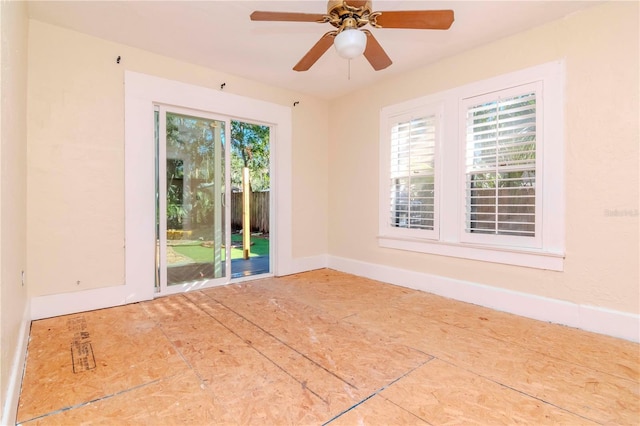 empty room featuring a healthy amount of sunlight, ceiling fan, and baseboards