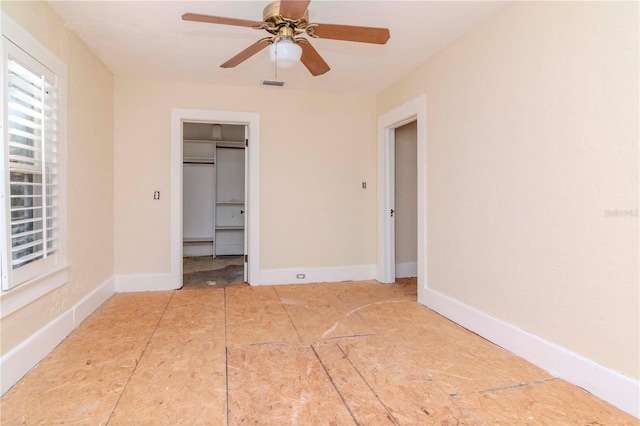 unfurnished bedroom with a spacious closet, a ceiling fan, visible vents, and baseboards