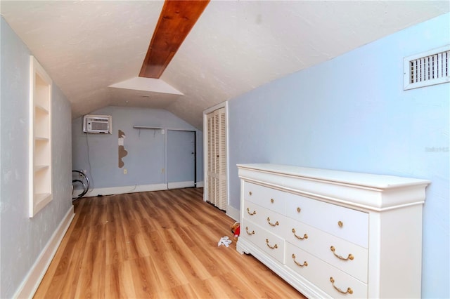 additional living space with lofted ceiling, visible vents, baseboards, a wall mounted AC, and light wood-type flooring