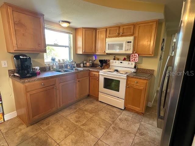 kitchen featuring white appliances, sink, and light tile patterned floors