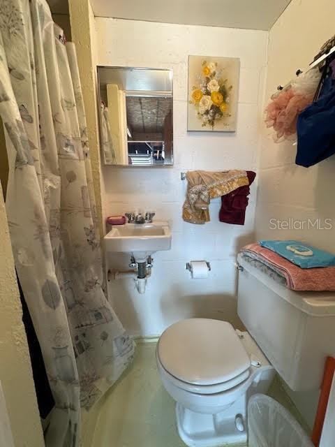 bathroom with a shower with shower curtain and toilet