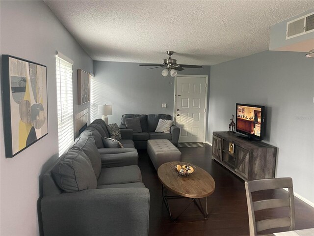 living room featuring ceiling fan, dark hardwood / wood-style flooring, and a textured ceiling