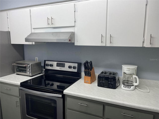 kitchen featuring gray cabinets, white cabinetry, stainless steel electric range oven, and exhaust hood