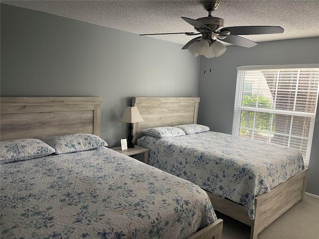 carpeted bedroom featuring ceiling fan and a textured ceiling