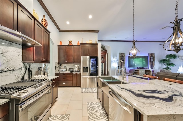 kitchen featuring sink, appliances with stainless steel finishes, tasteful backsplash, decorative light fixtures, and light stone counters