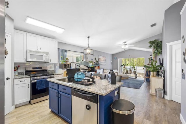 kitchen featuring blue cabinetry, an island with sink, lofted ceiling, white cabinets, and appliances with stainless steel finishes