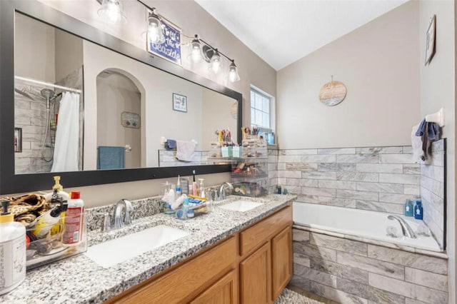 bathroom featuring vanity, a relaxing tiled tub, and vaulted ceiling