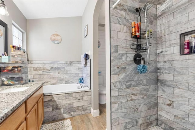 full bathroom featuring hardwood / wood-style floors, vanity, toilet, and shower with separate bathtub