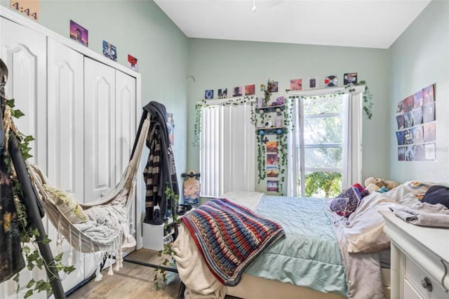 bedroom featuring vaulted ceiling, light wood-type flooring, and a closet