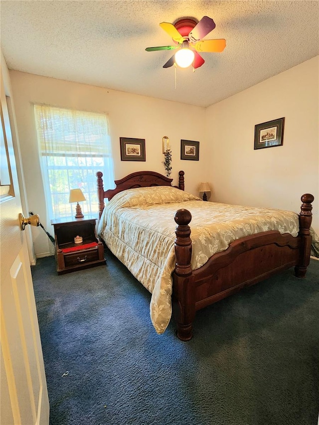 bedroom featuring a textured ceiling, dark carpet, and ceiling fan