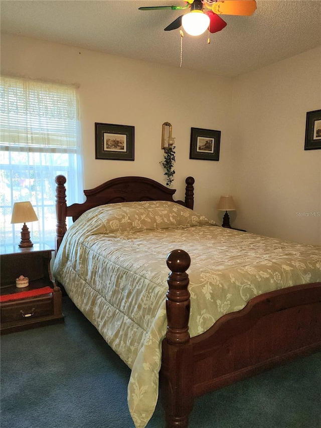 bedroom featuring ceiling fan, a textured ceiling, and dark colored carpet