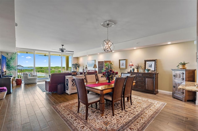 dining room with ceiling fan with notable chandelier and light wood-type flooring