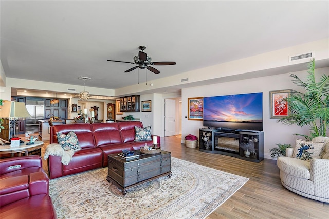 living room featuring hardwood / wood-style floors and ceiling fan with notable chandelier