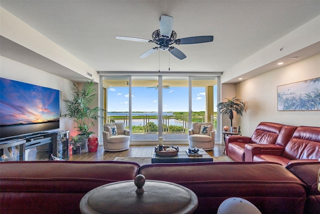 living room with a water view, ceiling fan, expansive windows, and hardwood / wood-style flooring